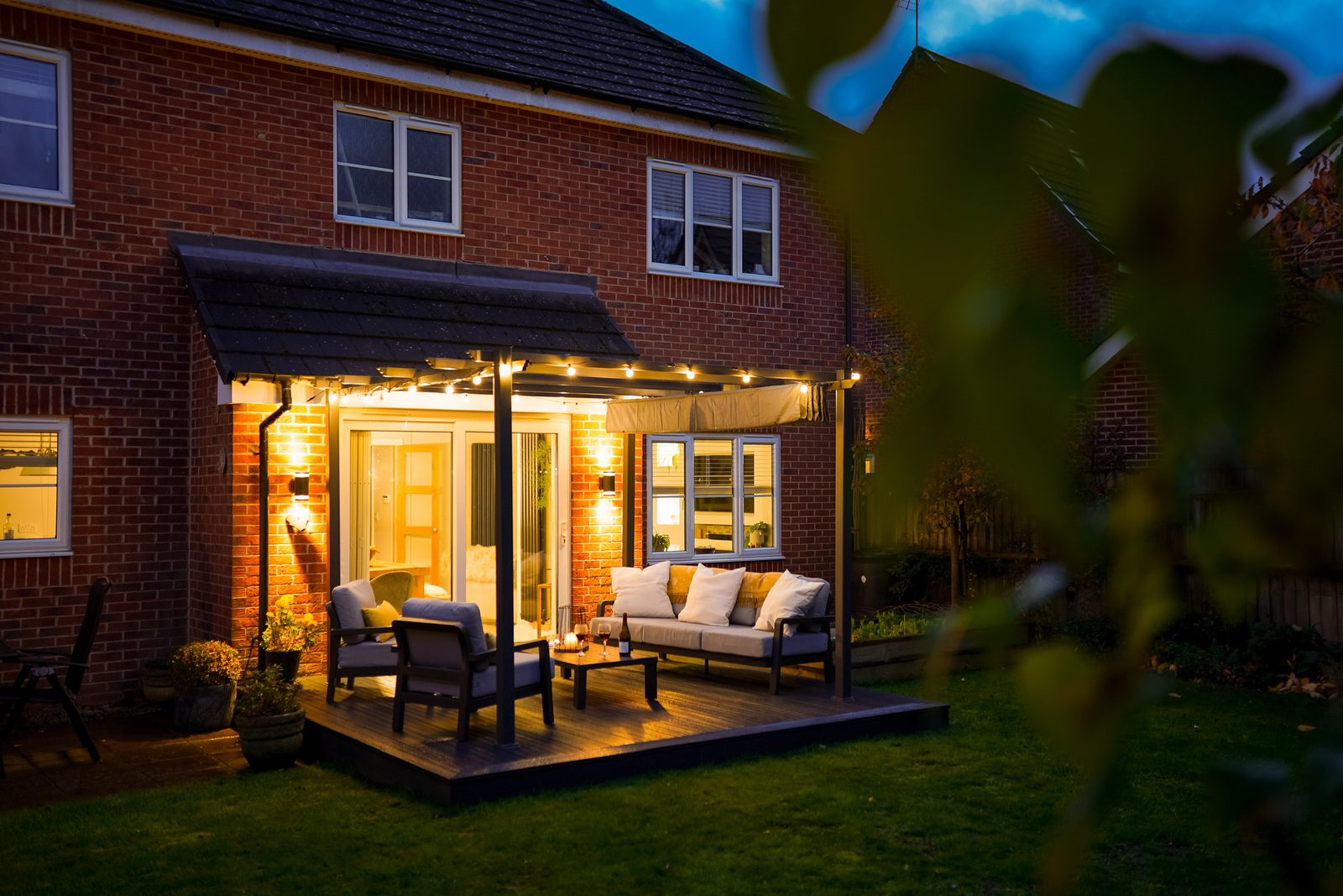 Aluminium veranda lit up over a patio at dusk
